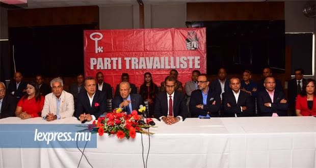 Conférence de presse du Parti Travailliste, responsables assis devant une bannière rouge