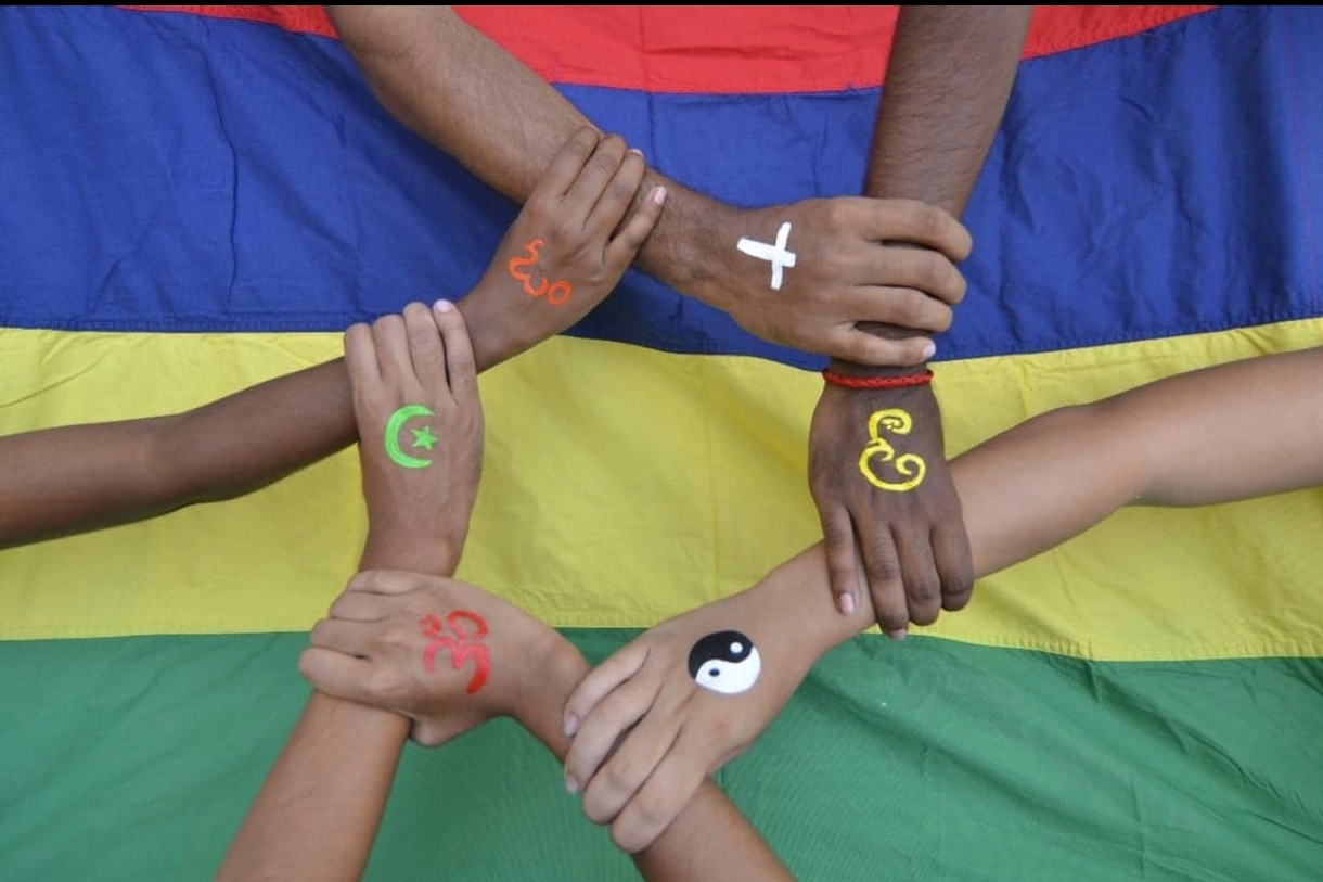 Mains unies devant le drapeau mauricien, symbolisant l'unité dans la diversité